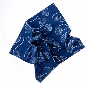 A loosely draped Lana Napkin with blue and white indigo block print of water lily seed pods.  