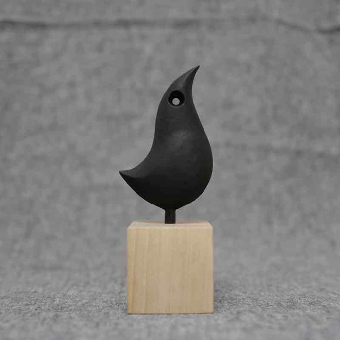 KAMASADA STUDIO Kingfisher Ornament on a wood pedestal sitting of a grey fabric. 